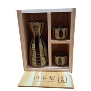Juego de sake de líneas oscuras sobre fondo ocre con 2 vasitos y caja de madera — fotografía 1